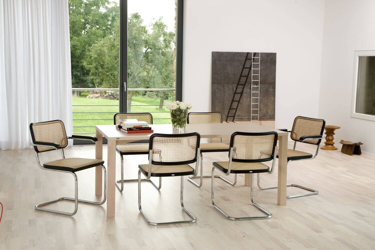 Esszimmer mit sechs modernen Stühlen, Holztisch, großen Fenstern und Wandkunst, Blick auf den Garten.