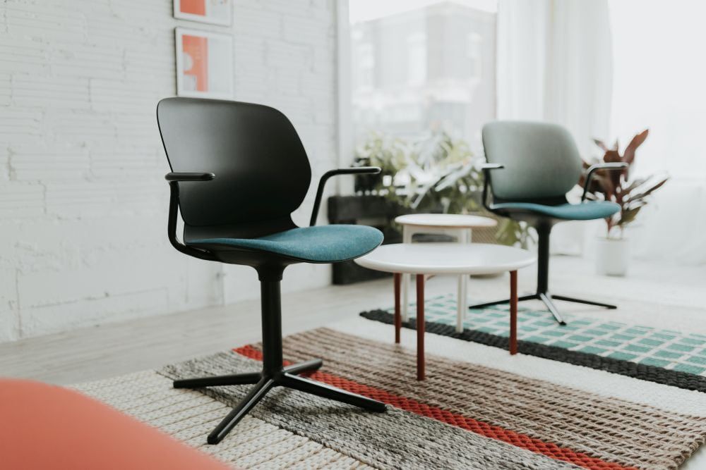 Zwei ergonomische Bürostühle mit stilvollem Design in einem modernen, hellen Raum mit Teppichen und Pflanzen.