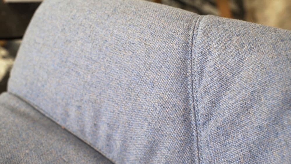 Nahaufnahme einer blauen Stoffpolsterung mit feiner Textur und klarer Naht.