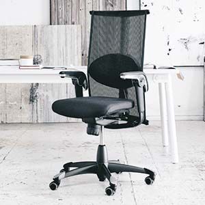 Schwarzer ergonomischer Bürostuhl mit Netzrückenlehne und Rollen, platziert vor einem weißen Schreibtisch.