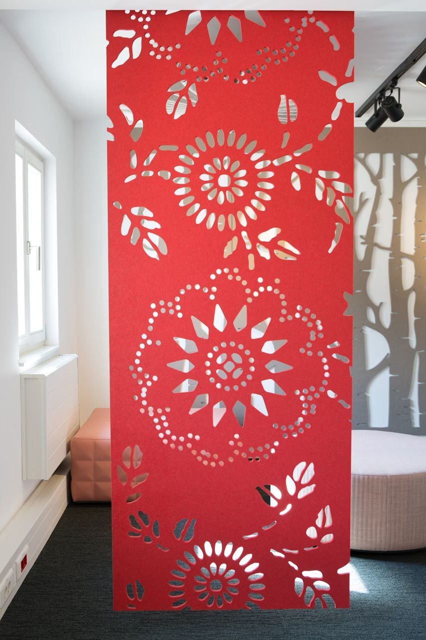 Roter Raumteiler mit floralem Muster, das Licht durchlässt, in einem modern eingerichteten Büroraum.