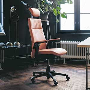 Ergonomischer Bürostuhl mit hoher Rückenlehne und Kopfstütze in modernem Raum mit Pflanzen und Fenstern.