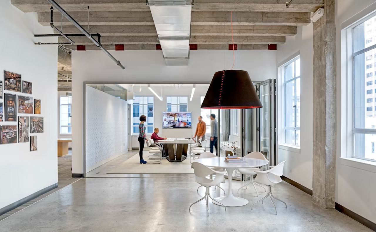 Modernes Büro mit Glastrennwand, ergonomischen Bürostühlen und Tischgruppe, ideal für dynamisches Arbeiten.