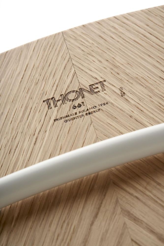 Nahaufnahme eines Thonet Holzmusters mit Gravur und weißem Stab im Vordergrund.