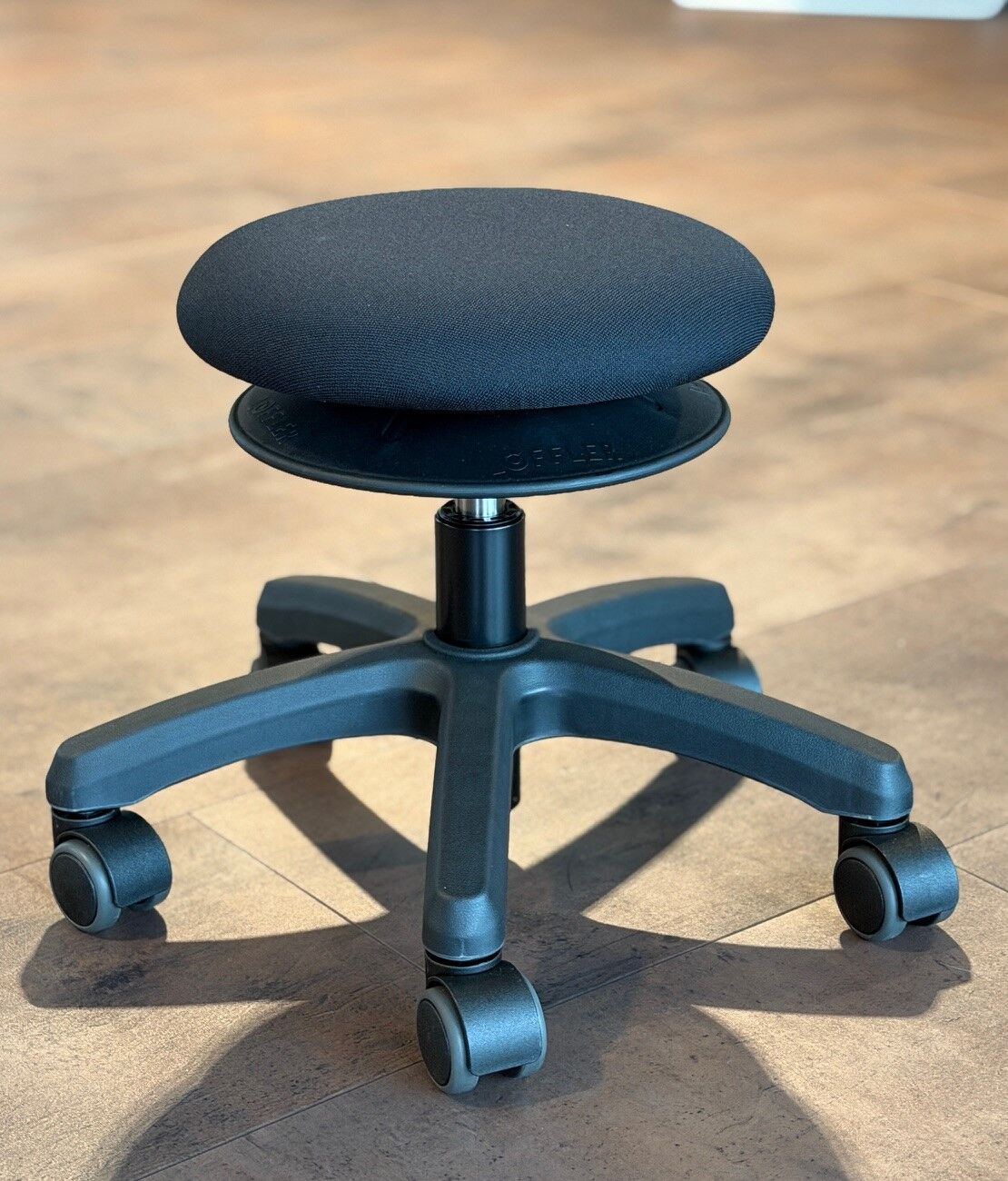 Moderner, ergonomischer Bürostuhl ohne Rückenlehne auf Rollen, ideal für bewegtes Sitzen im Büro.
