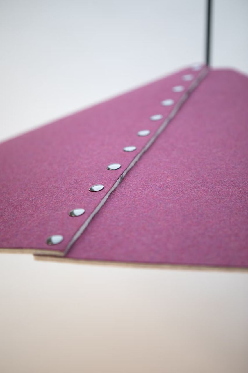 Nahaufnahme einer rosa stoffbezogenen Lampenschirmkante mit silbernen Nieten verziert.