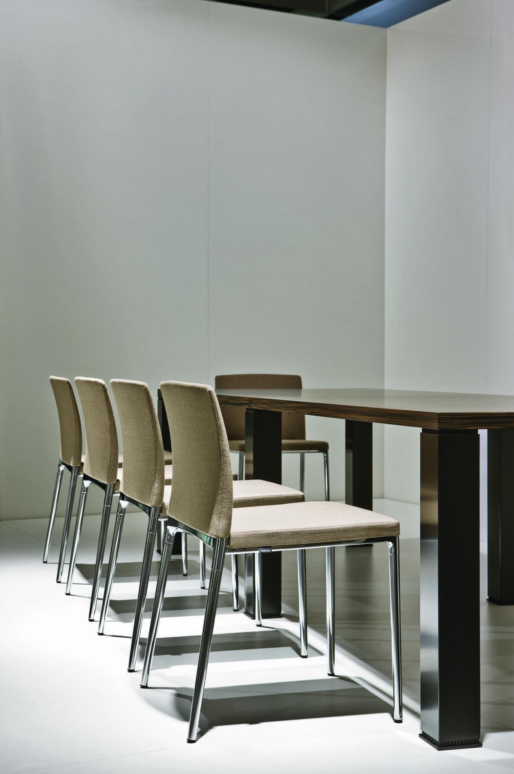 Moderne, minimalistische Essstühle mit Metallbeinen neben einem dunklen Holztisch in einem hellen Raum.