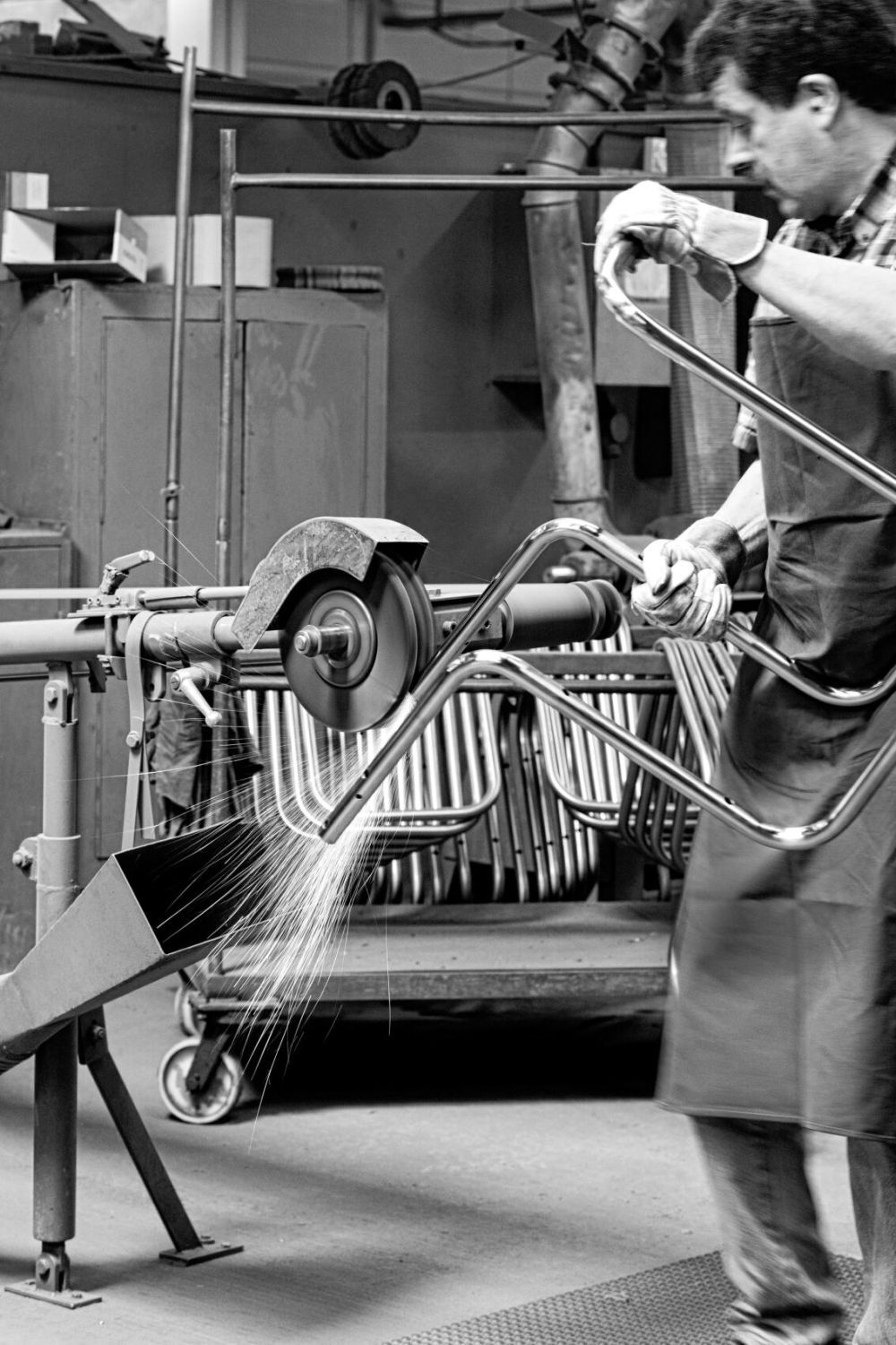 Industrielle Fertigung: Ein Arbeiter schleift ein Metallteil, Funken sprühen in einer Werkstattumgebung.