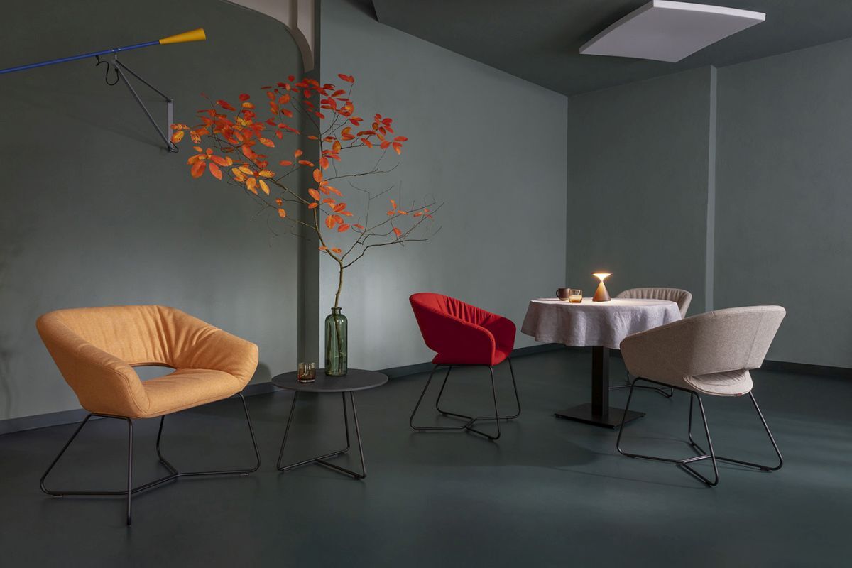 Design-Stühle in modernem Raum mit Tisch, sanfter Beleuchtung und herbstlichem Ast in Vase dekoriert.