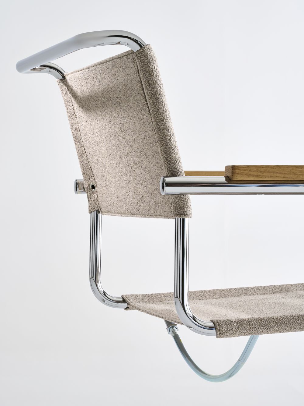 Detailansicht eines ergonomischen Stuhls mit verchromtem Metallrahmen und beigem Stoffbezug.