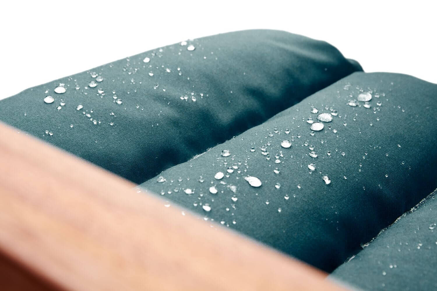 Nahaufnahme von wasserabweisendem Stoff mit Wassertropfen auf einer dunkelgrünen Polsterung.