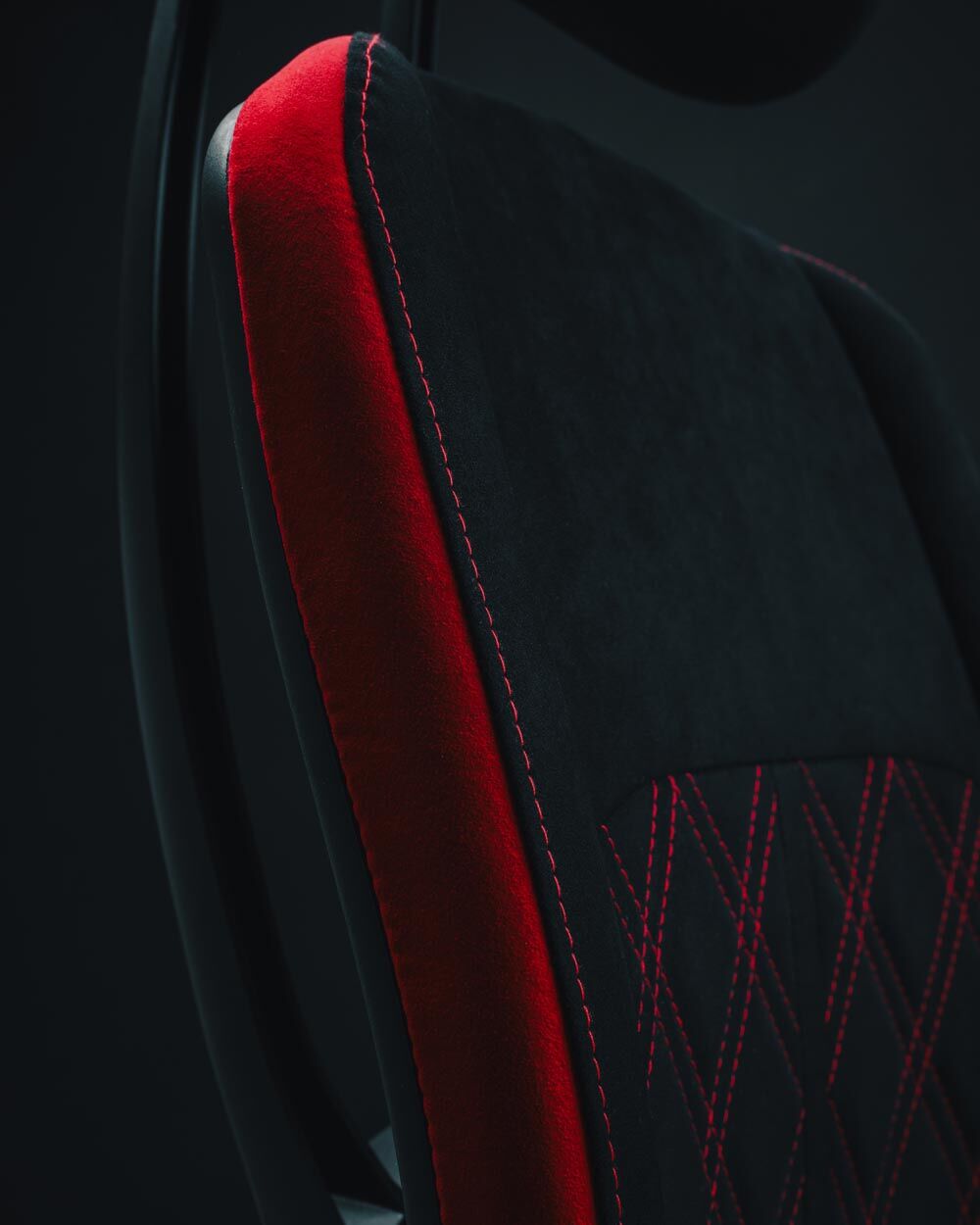 Nahaufnahme eines ergonomischen Stuhls mit schwarzem Bezug und roten Akzenten, Detail der Rückenlehne sichtbar.