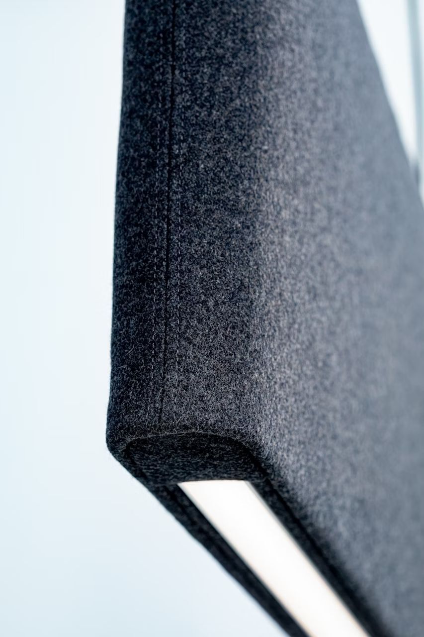 Nahaufnahme eines dunkelgrauen textilen Akustikpaneels mit klaren Kanten, ideal für moderne Büroeinrichtung.