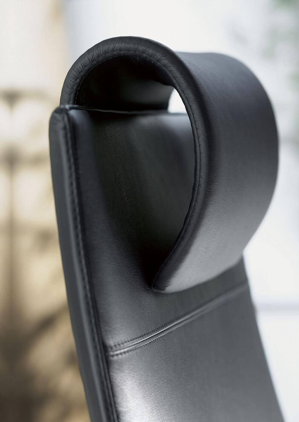 Detail einer ergonomischen schwarzen Lederkopflehne eines Bürostuhls mit modernem Design.