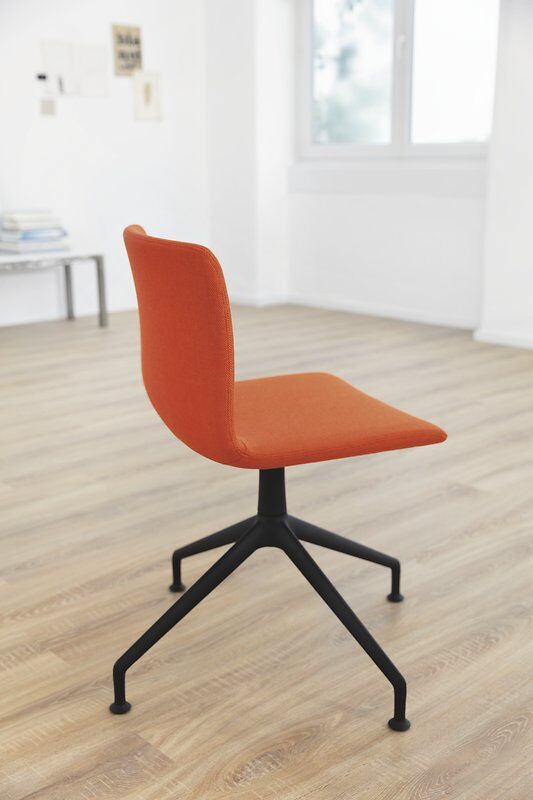 Ergonomischer Stuhl mit orangefarbenem Sitz und schwarzem Metallgestell auf Holzfußboden in modernem Büro.