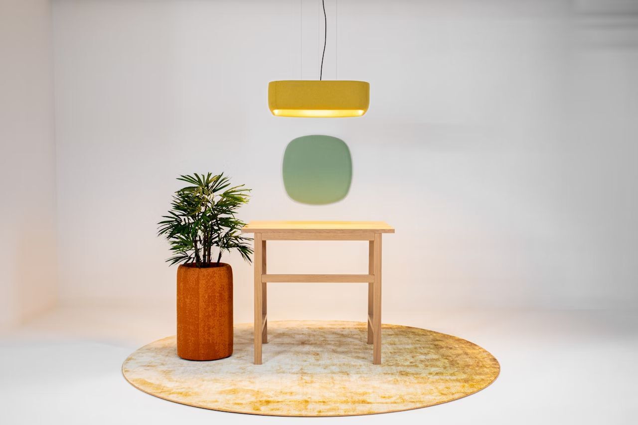 Moderne Einrichtung mit Holzschreibtisch, Hängelampe und Zierpflanze auf rundem Teppich in hellem Raum.