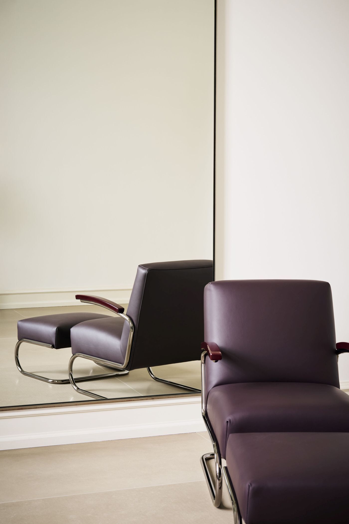 Moderner ergonomischer Stuhl mit Chromgestell und lila Polsterung vor einem Spiegel.