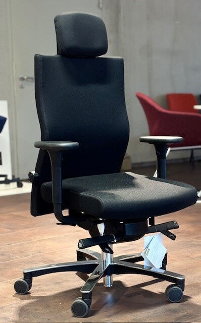 Ergonomischer Bürostuhl mit schwarzer Polsterung, verstellbaren Armlehnen und Kopfstütze auf Holzboden abgebildet.