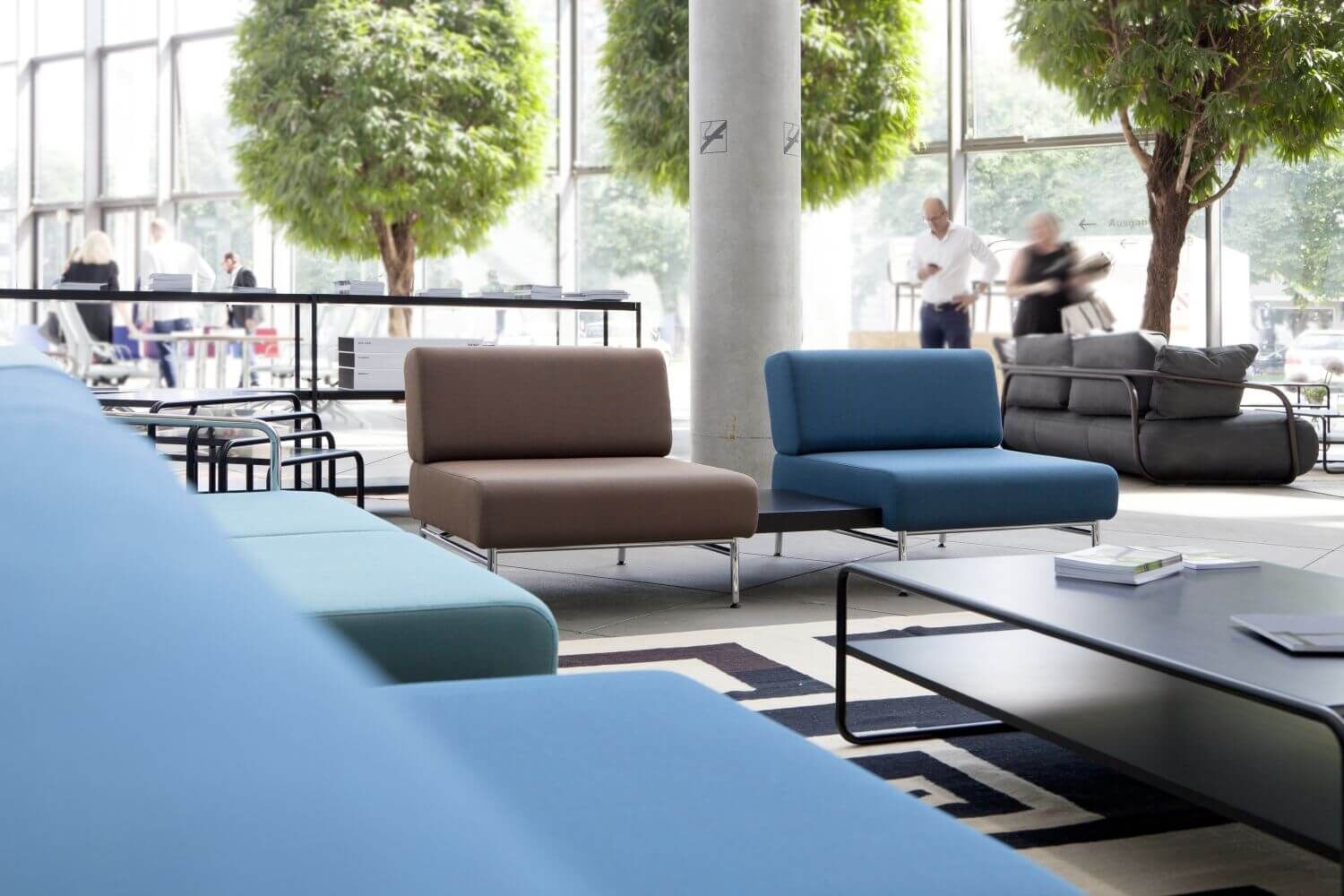 Modernes Büro mit ergonomischen Sitzmöbeln und großen Pflanzen in einem lichtdurchfluteten Raum.