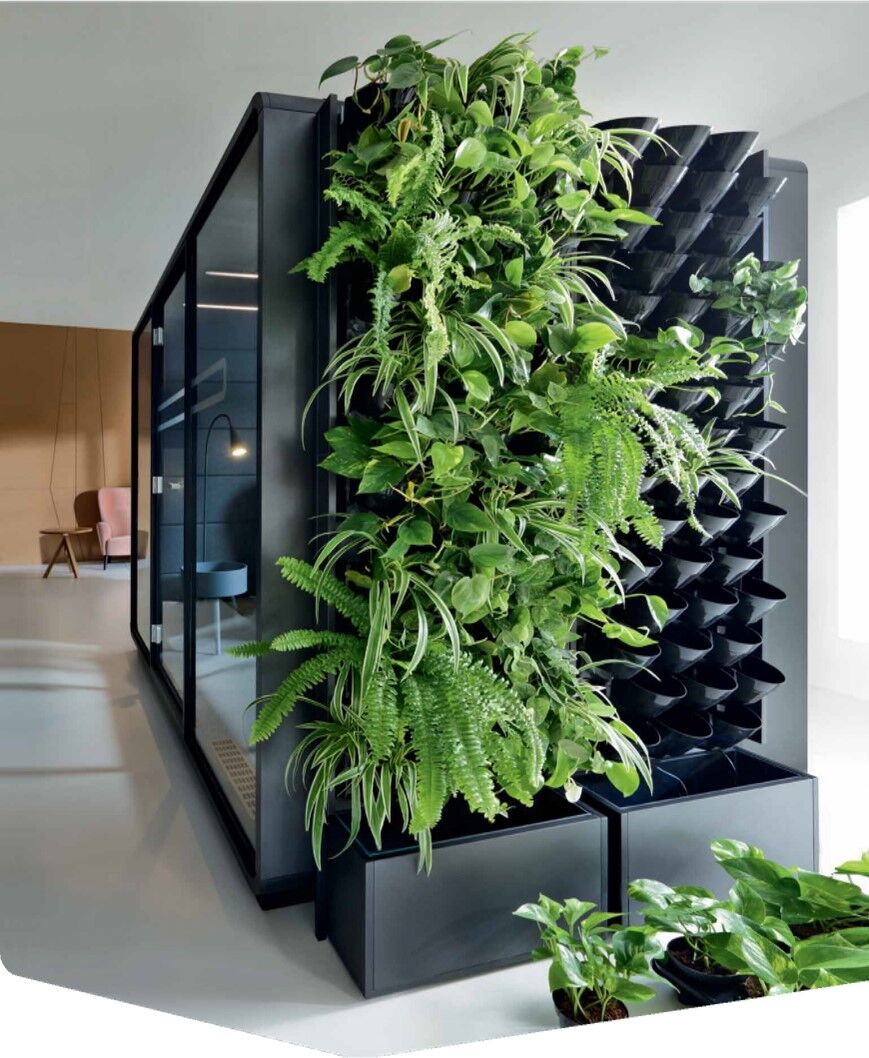 Ein moderner Büroraum mit einer grünen Pflanzenwand, die Frische und Natur in das Büro bringt.