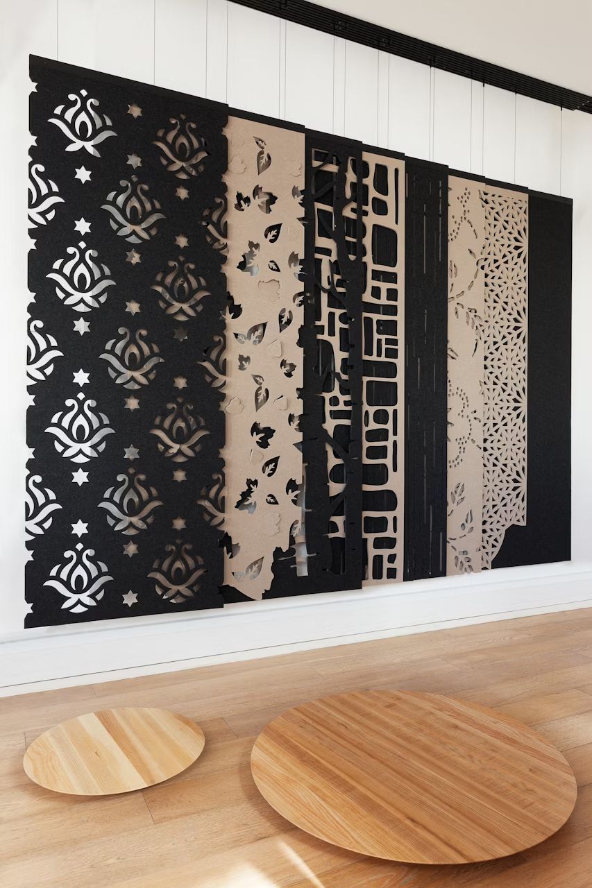 Dekorative Wandpaneele mit komplexen Mustern in Schwarz und Beige, auf hochwertigem Holzboden präsentiert.