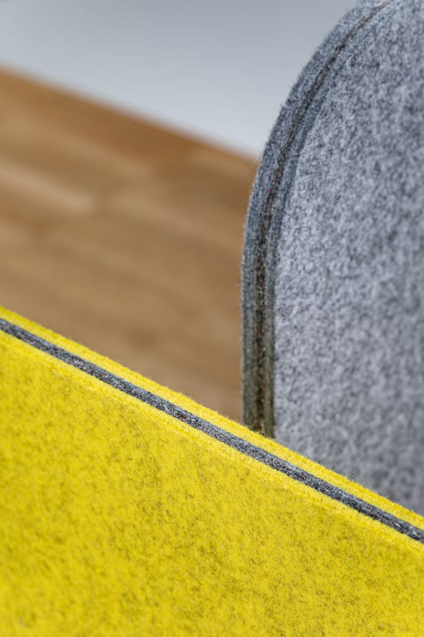 Detailaufnahme von grauen und gelben Filztrennwänden in einem modernen Büro oder Homeoffice.