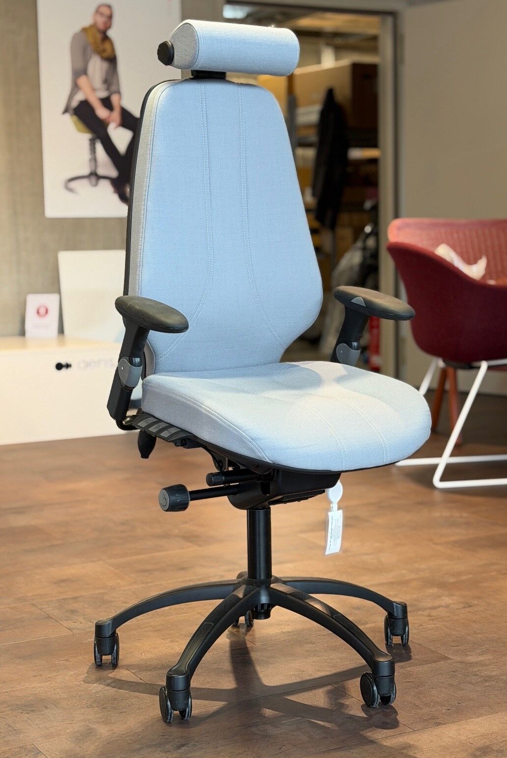 Ergonomischer Bürostuhl mit blauer Polsterung, verstellbarer Kopfstütze und Armlehnen in einem modernen, stilvollen Raum.