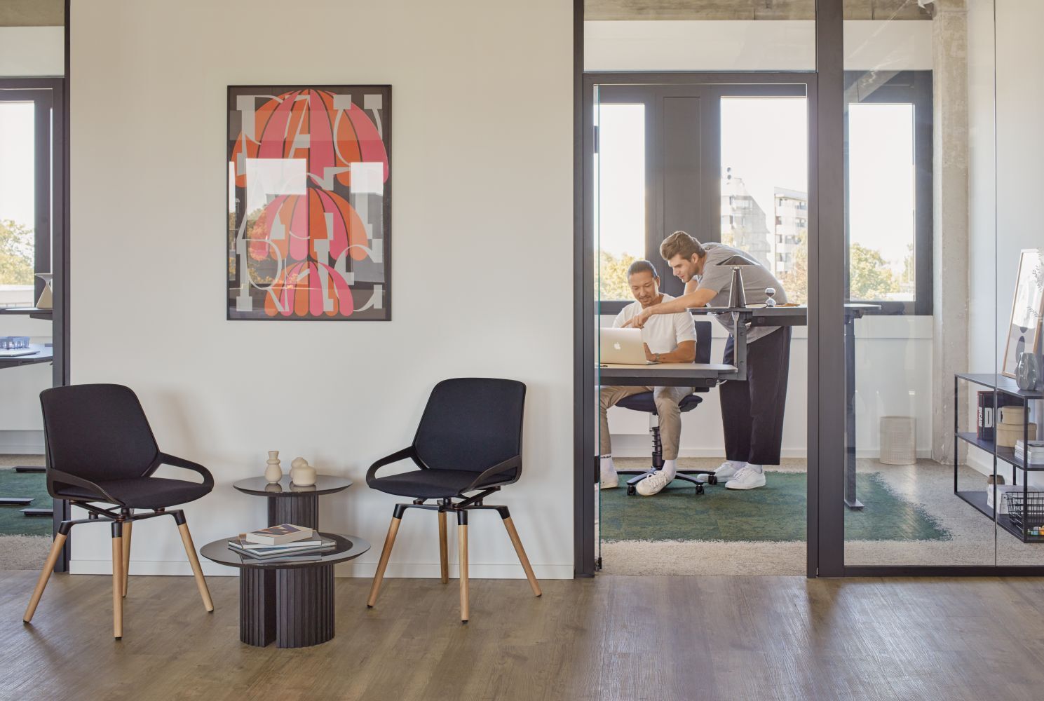 Moderne Büroeinrichtung mit ergonomischen Stühlen, ein Tisch und zwei Personen an einem Laptop in einem stilvollen Raum.