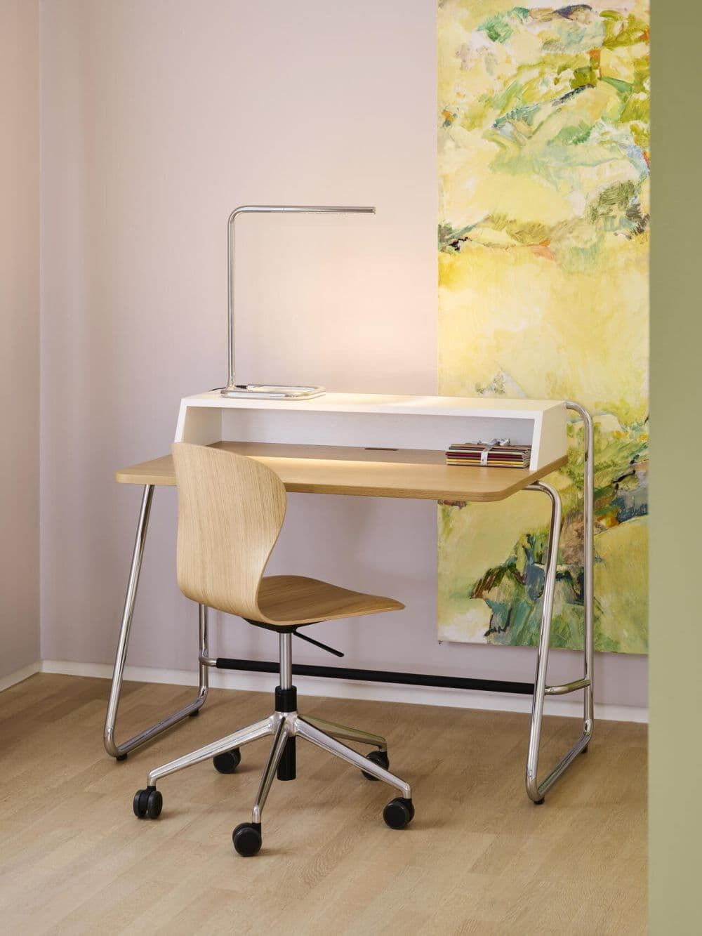 Moderner ergonomischer Schreibtisch mit Holzstuhl auf Rollen und dekorativer Wandkunst im Büro.
