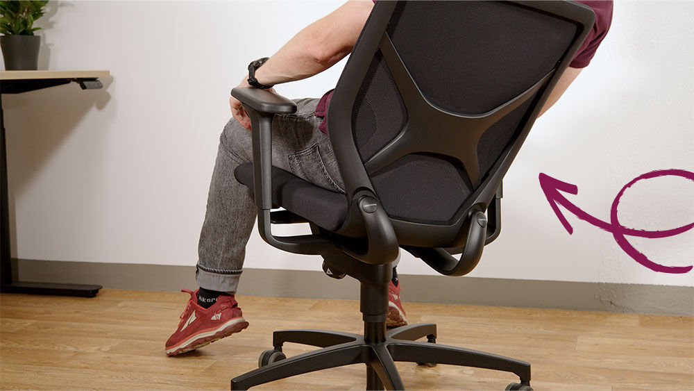 Person zeigt dynamisches Sitzen auf ergonomischem Bürostuhl mit verstellbaren Armlehnen und Rücklehne.