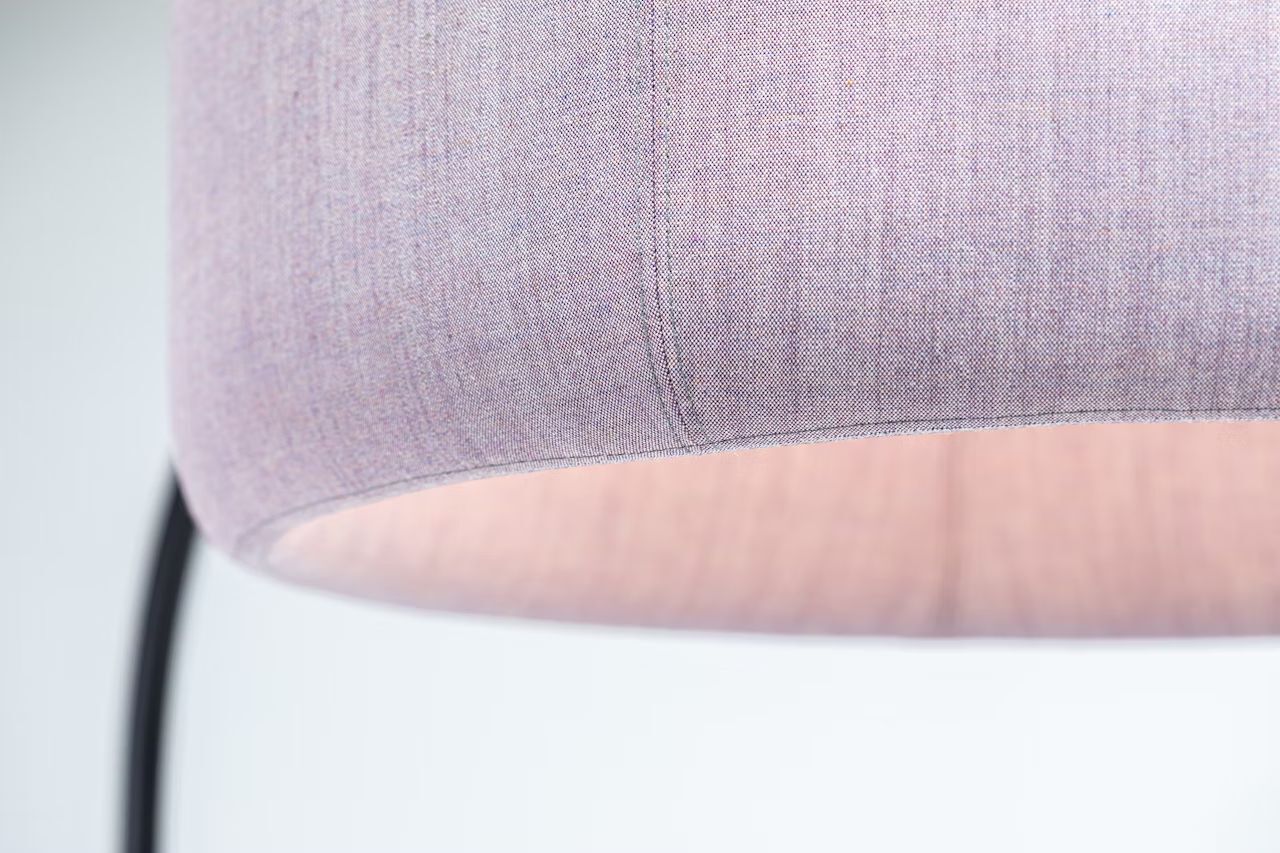 Nahaufnahme eines Stofflampenschirms mit sanftem rosa Licht, das durch den Stoff scheint.