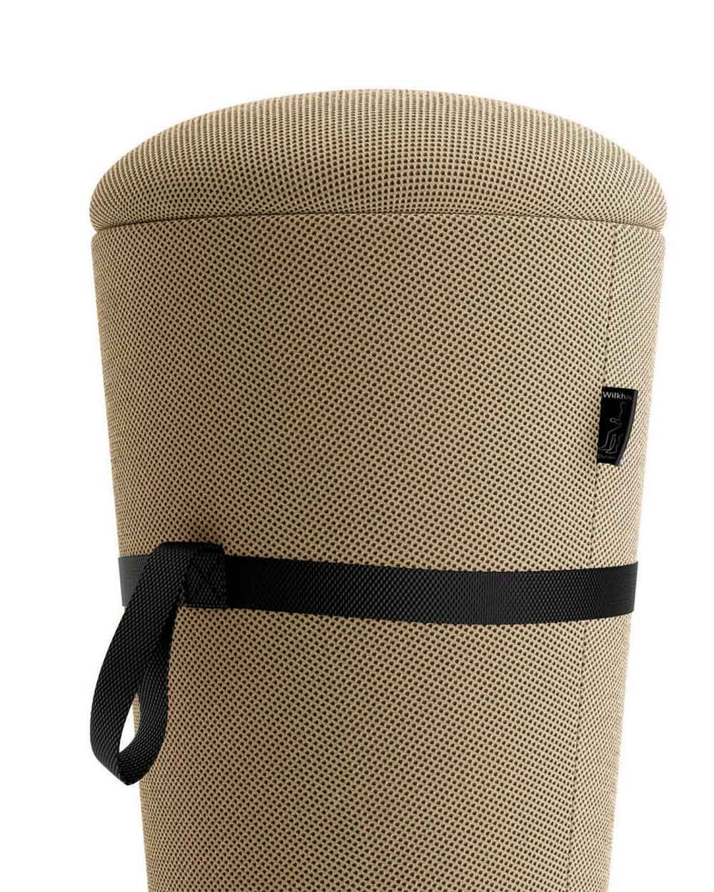 Ergonomischer Sitzhocker mit hellbraunem Stoffbezug, schwarzem Tragegurt und gewebter Textur.