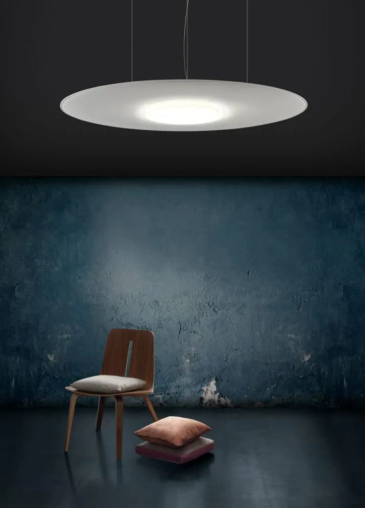 Moderner Raum mit hölzernem Stuhl, Kissen und stilvoller Deckenleuchte vor blauem Wandhintergrund.