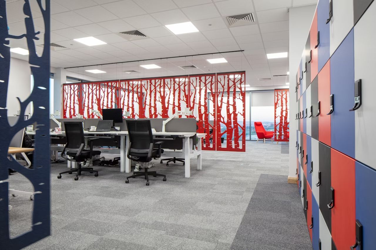Modernes Büro mit ergonomischen Stühlen, Schreibtischen und farbenfrohen Raumteilern, die ein kreatives Arbeitsumfeld schaffen.