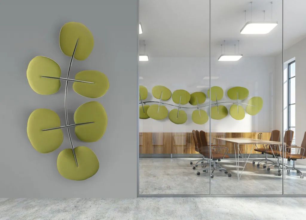 Modernes Büro mit grünen, blattförmigen Akustikpaneelen an der Wand und Glastür, Konferenztisch und Drehstühlen.