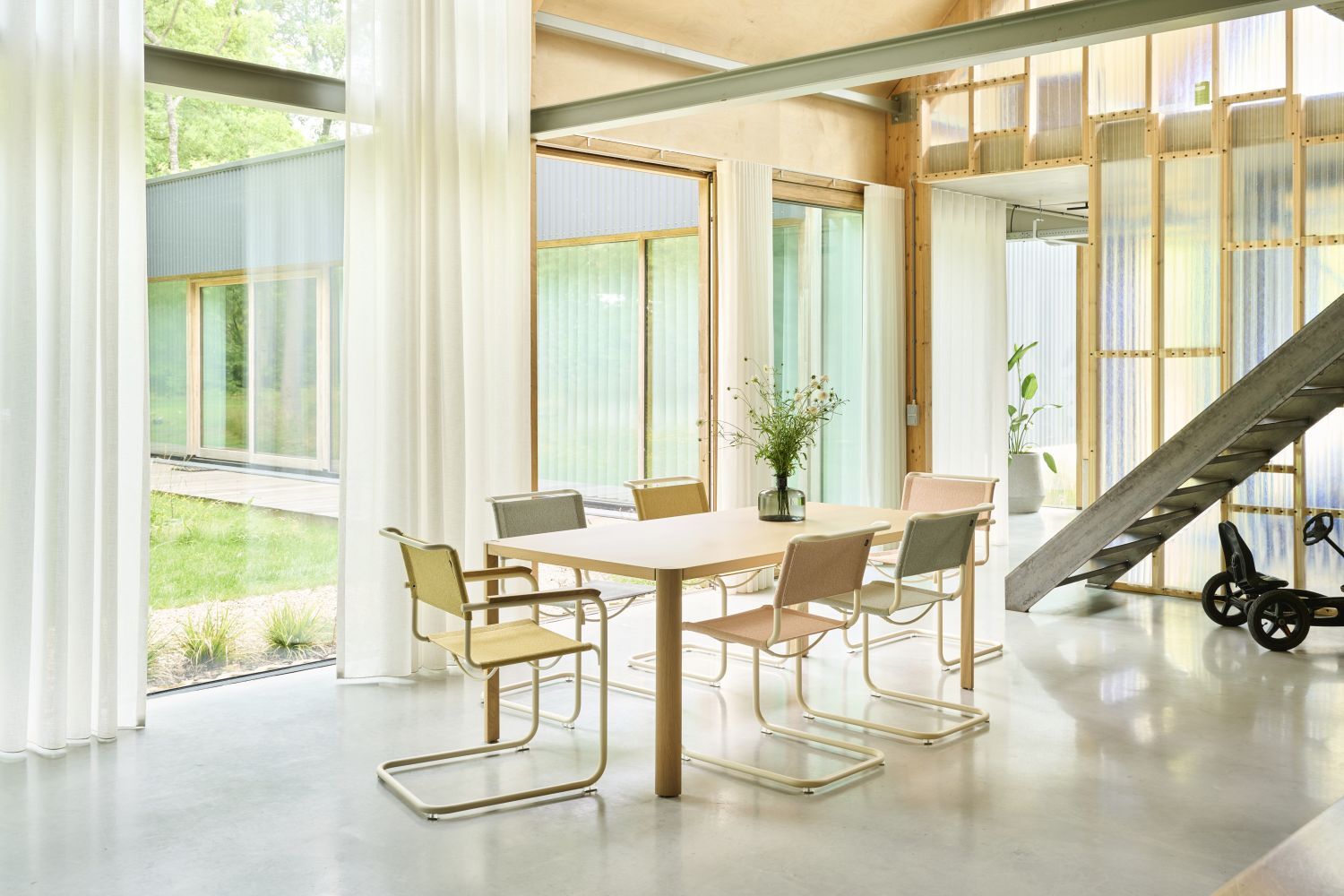 Ein heller, moderner Besprechungsraum mit Tisch, sechs ergonomischen Stühlen und großen Fenstern mit Blick auf Garten.