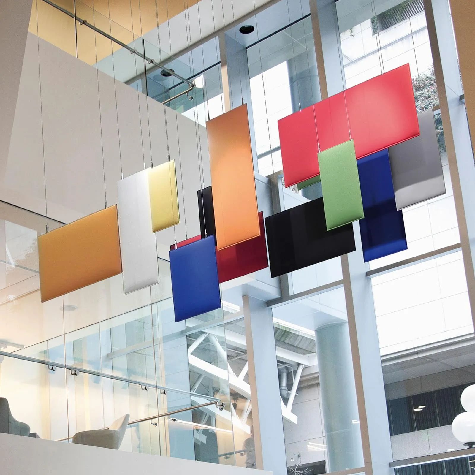 Farbenfrohe akustische Platten hängen in modernem Bürogebäude, verbessern Klang und Ästhetik des Raumes.