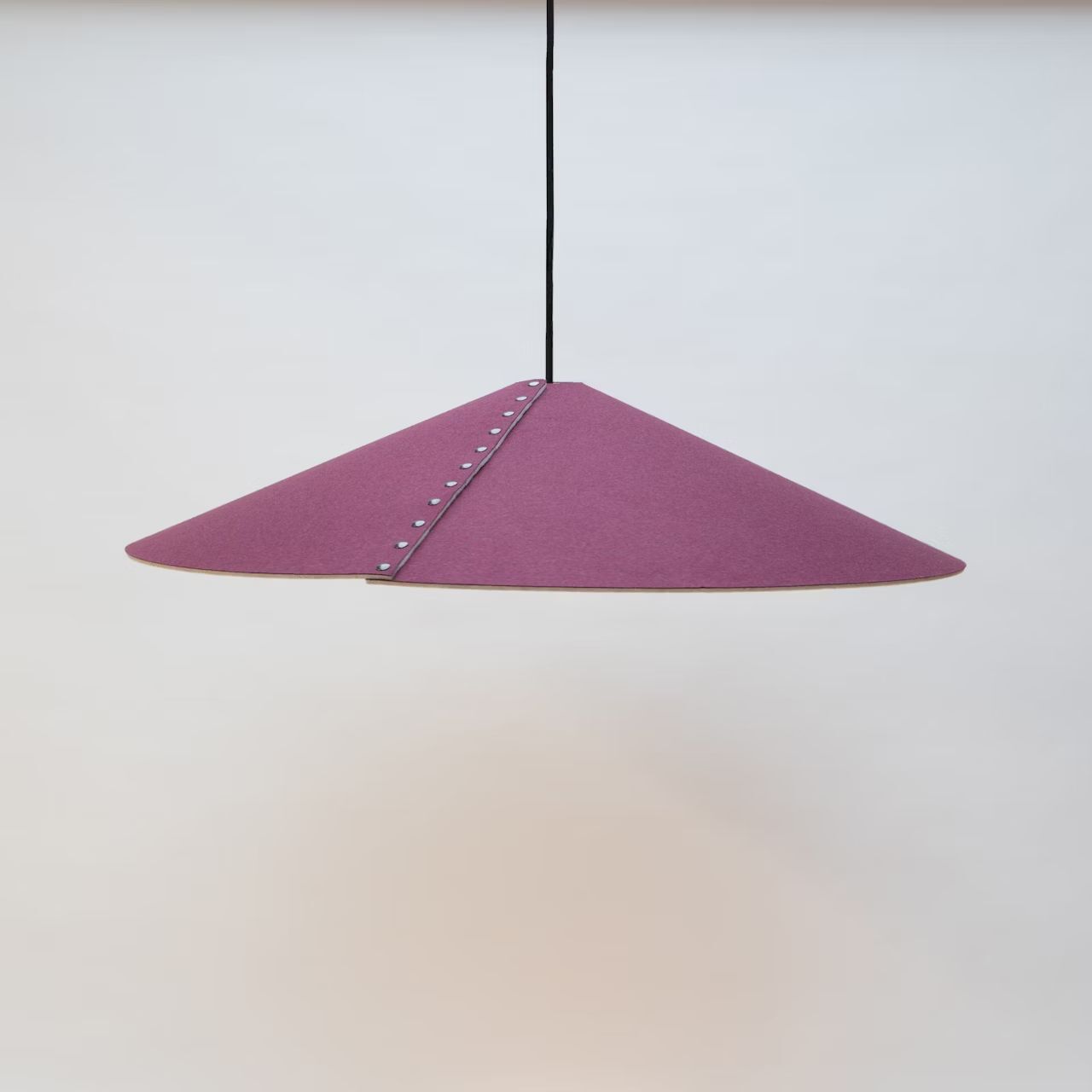 Pendelleuchte mit lila Filzschirm und Nieten, an schwarzem Kabel hängend, minimalistisches Design.