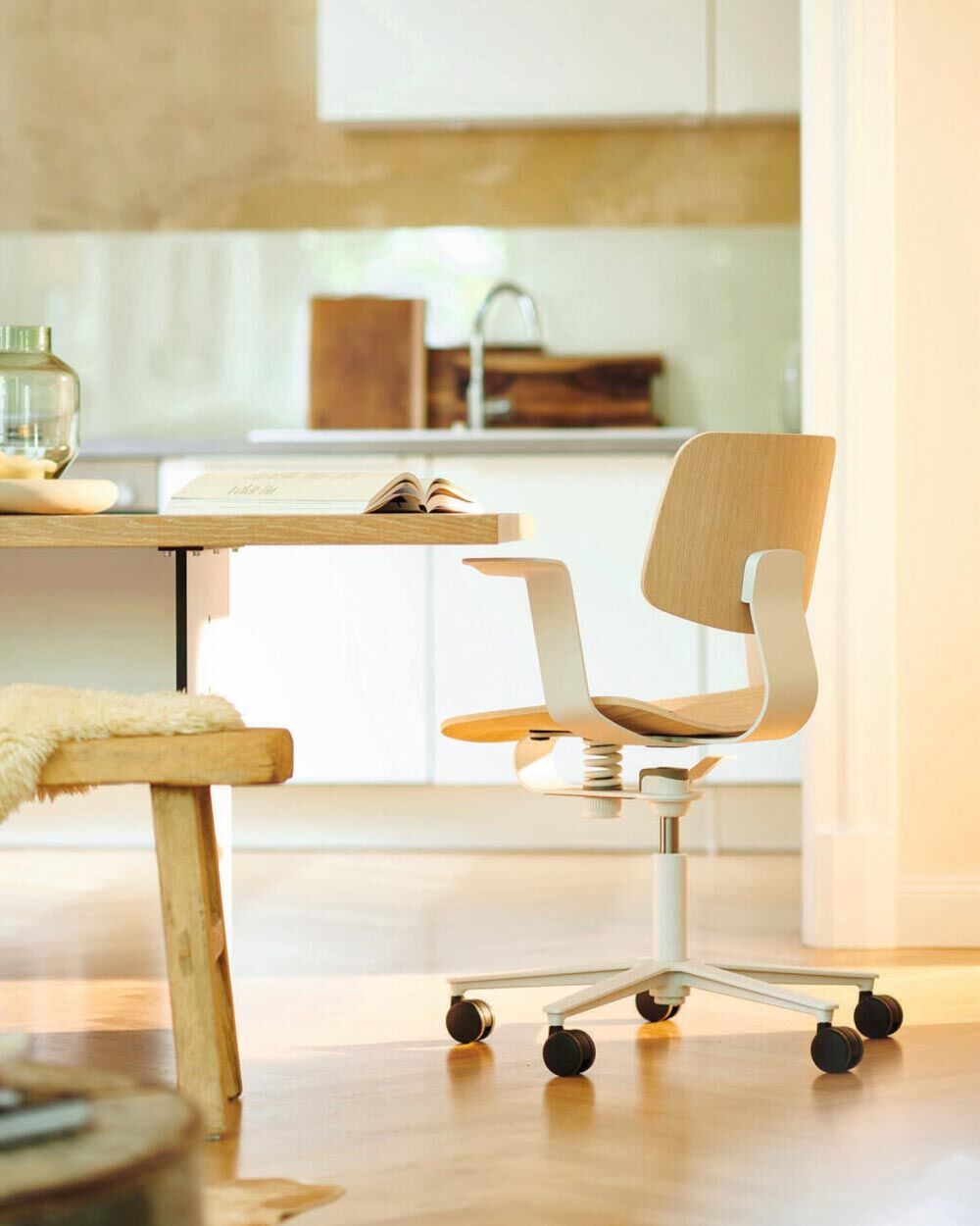 Moderner ergonomischer Bürostuhl aus Holz und Metall in einem hellen, stilvollen Raum neben einem Tisch.