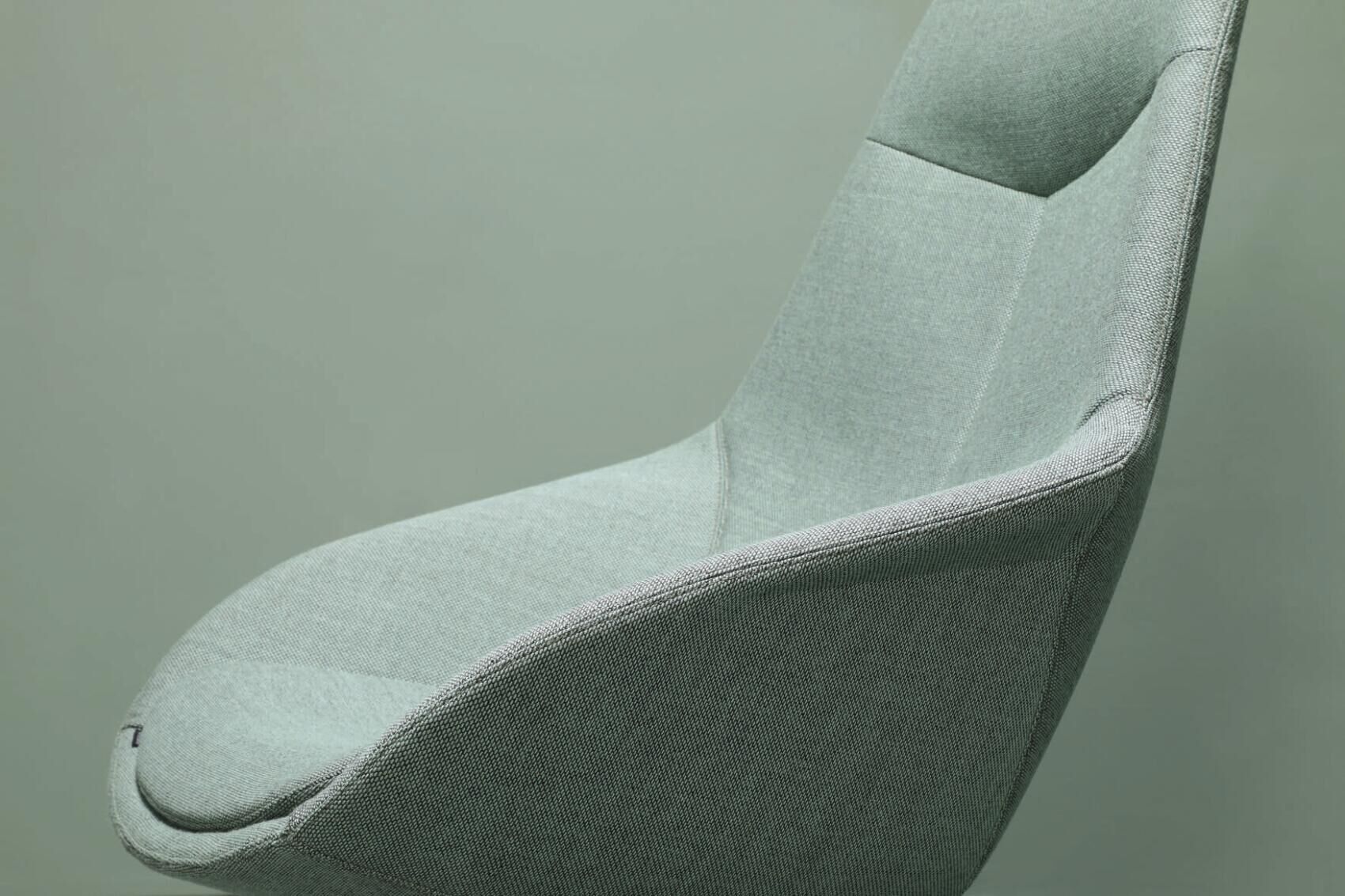 Nahaufnahme eines ergonomischen Stuhls in Hellgrün, betont die Textur und geschwungene Form des Designs.