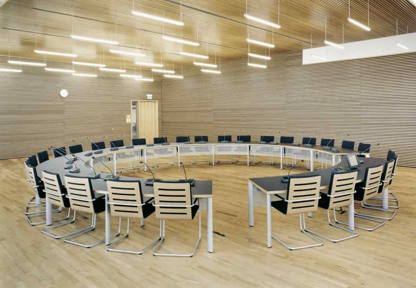 Moderner Konferenzraum mit ergonomischen Stühlen und U-förmigem Tischaufbau, ideal für Meetings und Präsentationen.