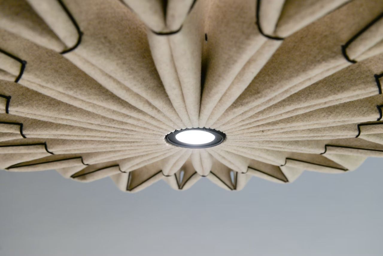 Nahaufnahme einer modernen Deckenleuchte mit filzartigem Design und zentralem leuchtendem Element.