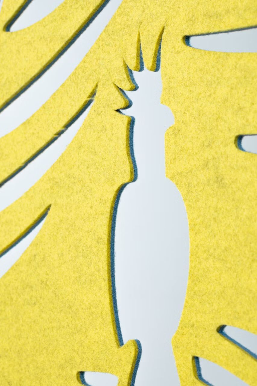 Nahaufnahme eines gelben Filzmotivs, das die Silhouette eines exotischen Vogels zeigt.