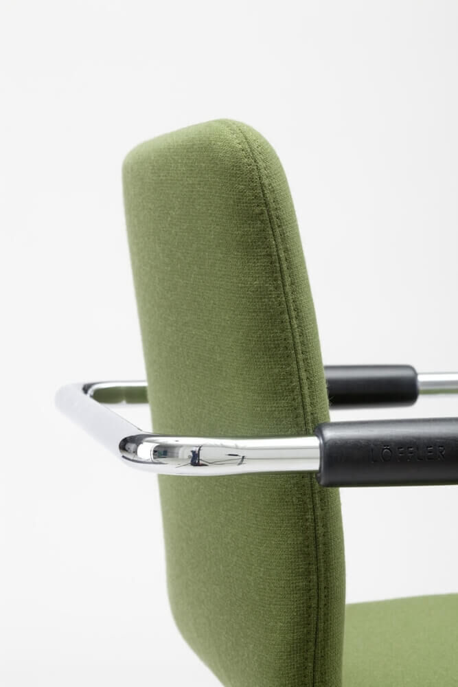Grüner ergonomischer Bürostuhl-Rücken mit verchromtem Griff und gepolstertem Stoffbezug.