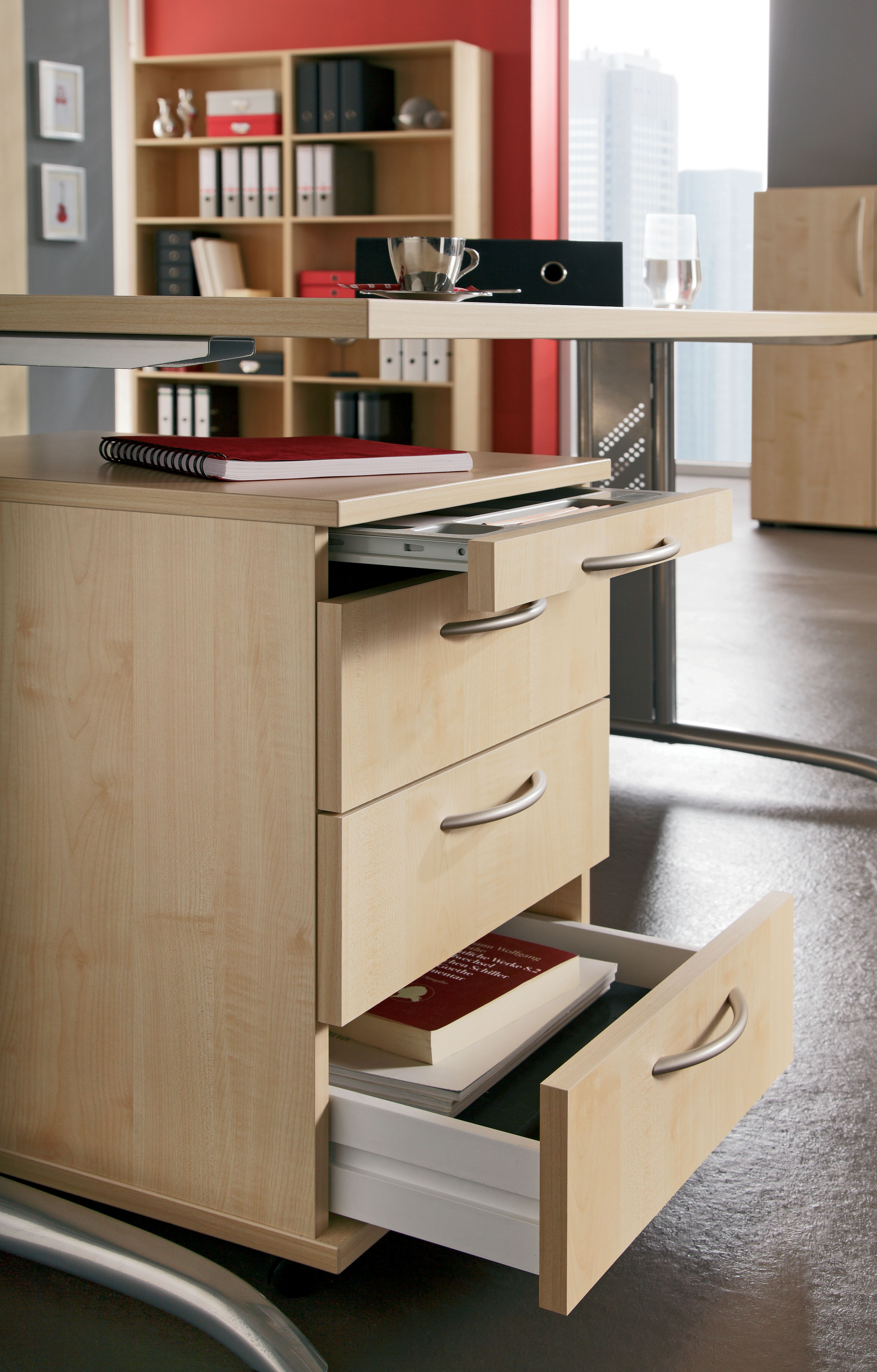 Moderner Büroschreibtisch mit offenen Schubladen, Notizbüchern und Büroordnern im Hintergrund, fördert organisierte Arbeitsumgebung.