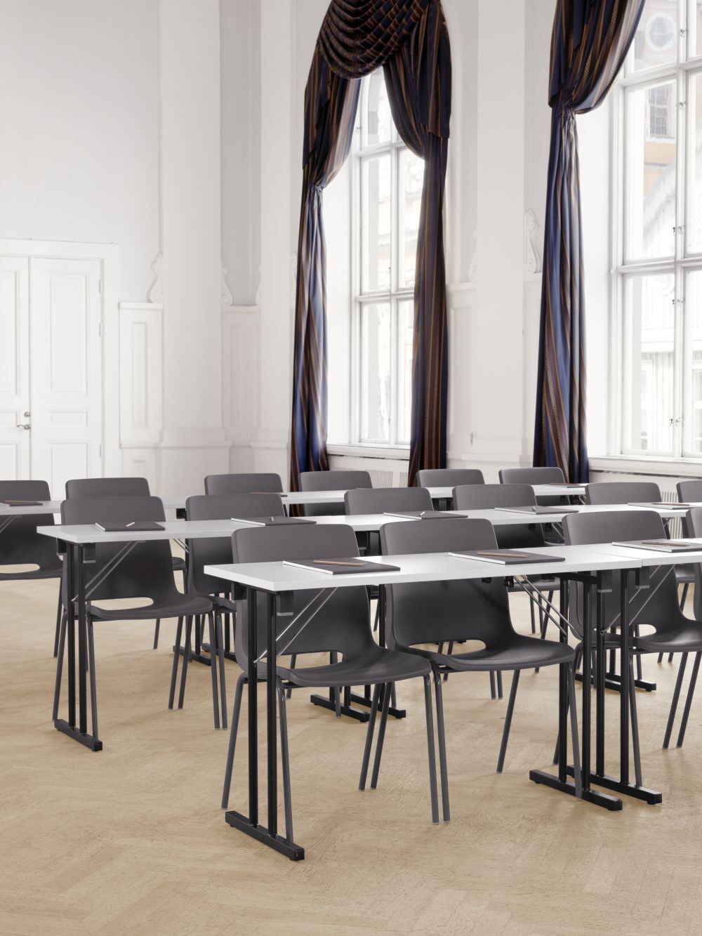Moderne Klassenzimmer mit grauen Stühlen und weißen Tischen in einem hellen, eleganten Raum.
