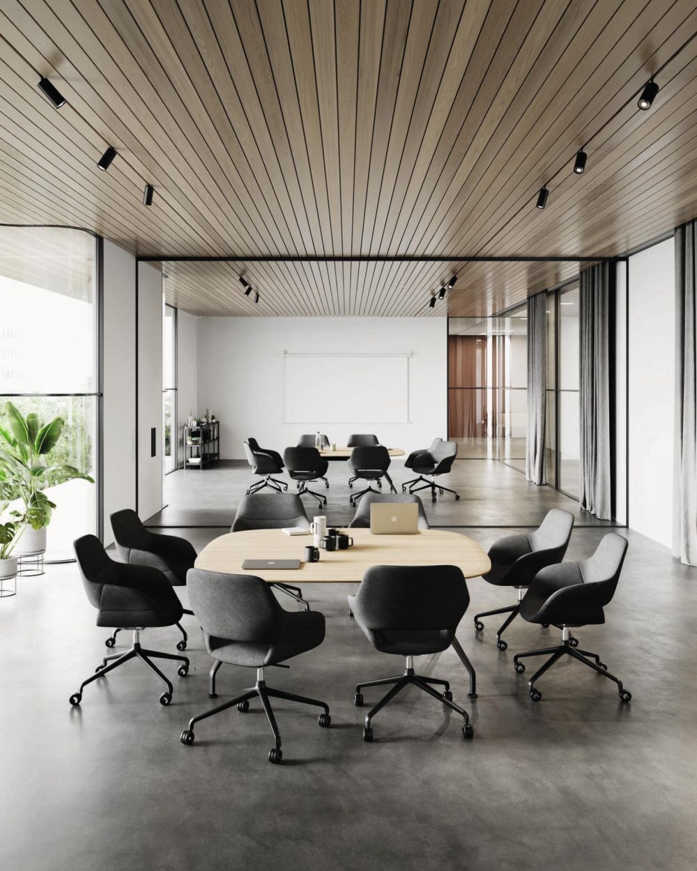 Moderner Konferenzraum mit ergonomischen, dunklen Bürostühlen um zwei große Tische, Holzakzente und Pflanzen.