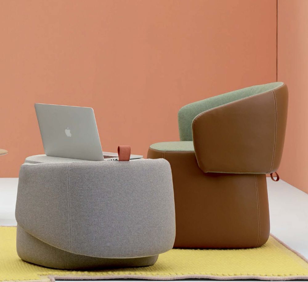 Ergonomische Bürostühle mit modernem Design, grauer Ottoman mit Laptop, vor pfirsichfarbener Wand.