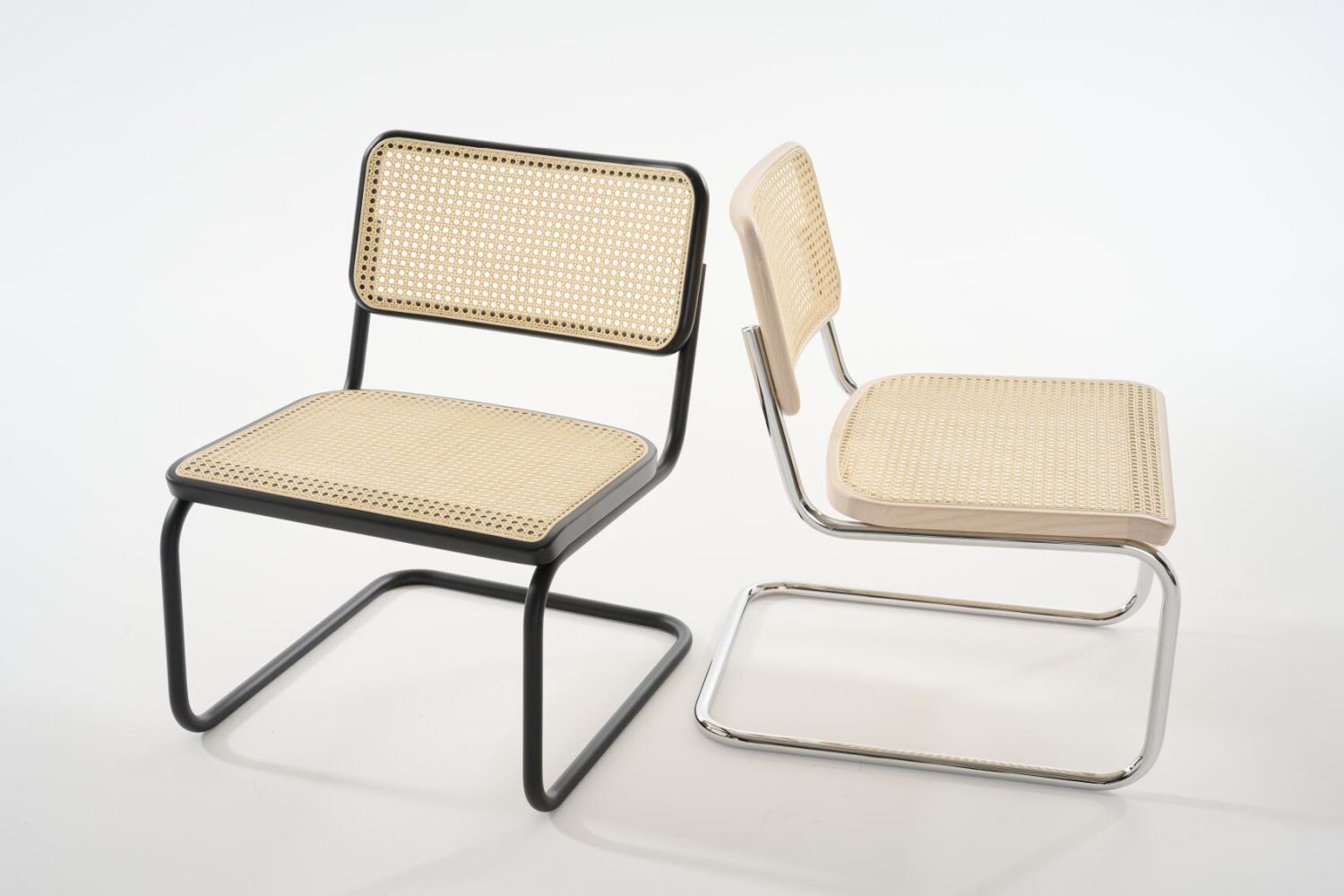 Zwei ergonomische Freischwingerstühle mit Geflecht, moderne Stahlrahmen in Schwarz und Chrom, auf weißem Hintergrund.