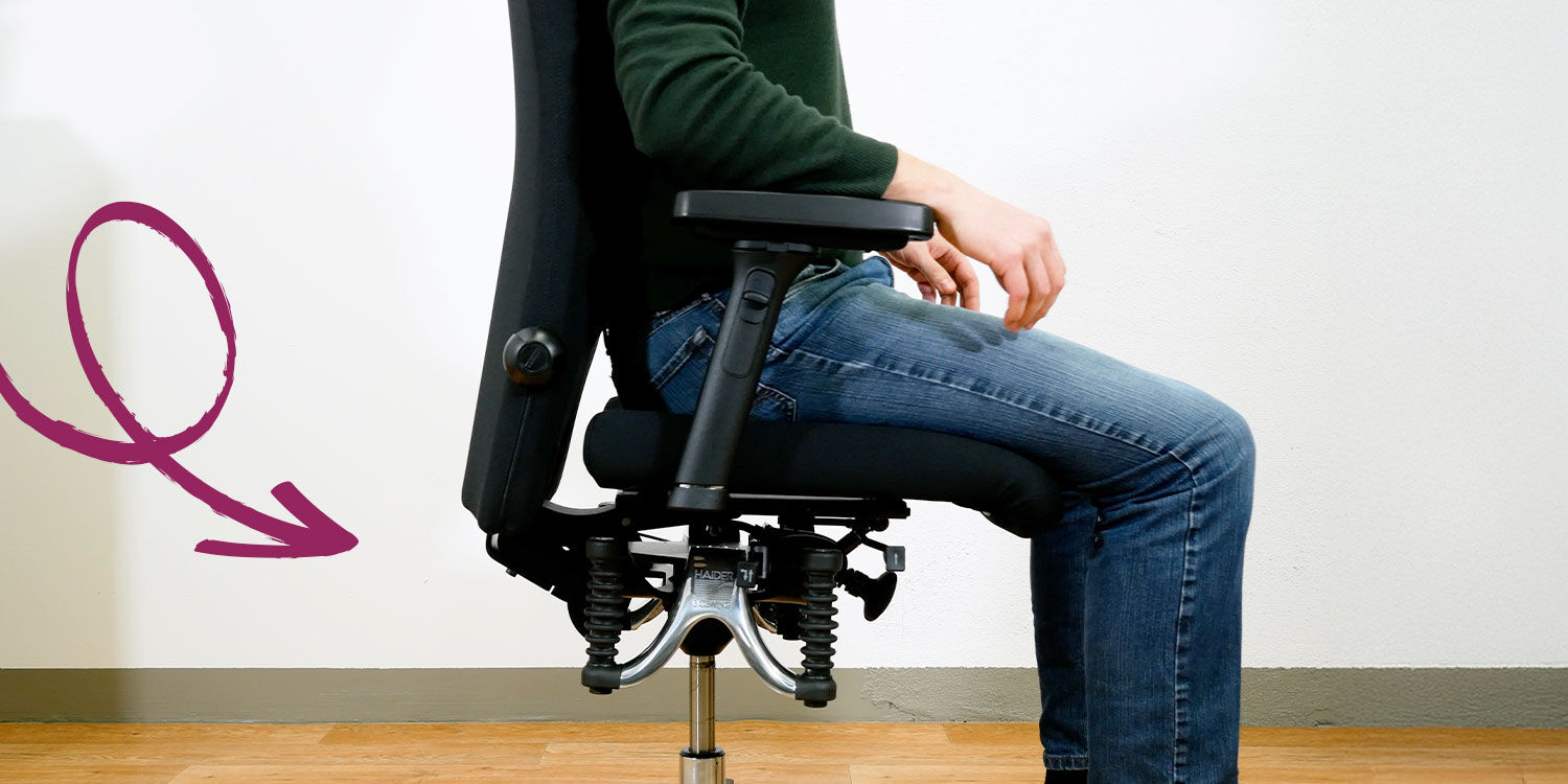 Person sitzt auf ergonomischem Bürostuhl mit verstellbarer Armlehne und dynamischem Sitzmechanismus.